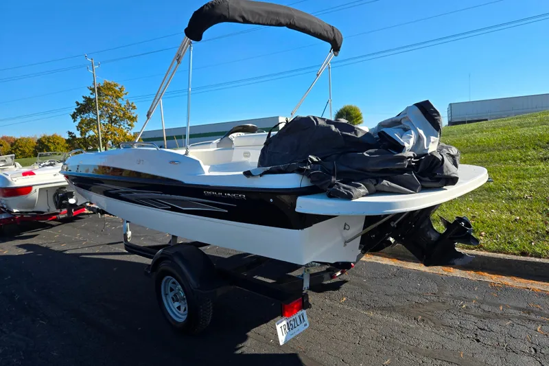 Slide: The Image of 2011 Bayliner 197 boat on trailer, parked outdoors under clear blue sky. - 3