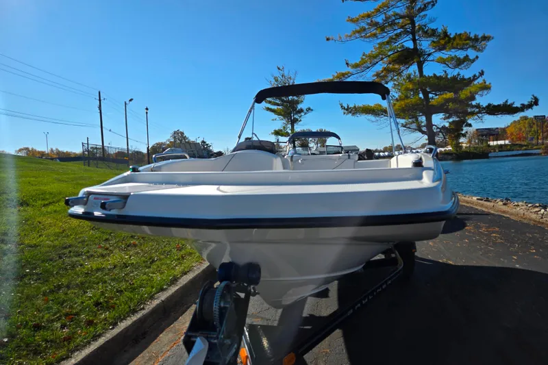 Slide: The Image of 2011 Bayliner 197 boat on trailer by a lakeside, under clear blue sky. - 6