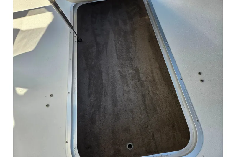 Slide: The Image of Storage compartment of a 2005 Stingray 195 LR boat, featuring a dark carpeted interior. - 16