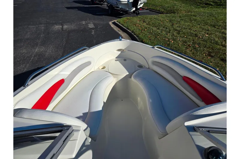 Slide: The Image of 2005 Stingray 195 LR boat interior with white and red seating, parked on pavement. - 17