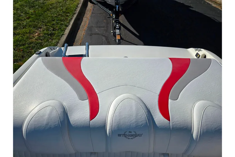 Slide: The Image of 2005 Stingray 195 LR boat seat with red and gray accents, parked on a street. - 22