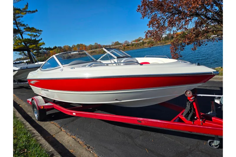 Slide: The Image of 2005 Stingray 195 LR boat on trailer by a lake, under clear blue sky. - 8