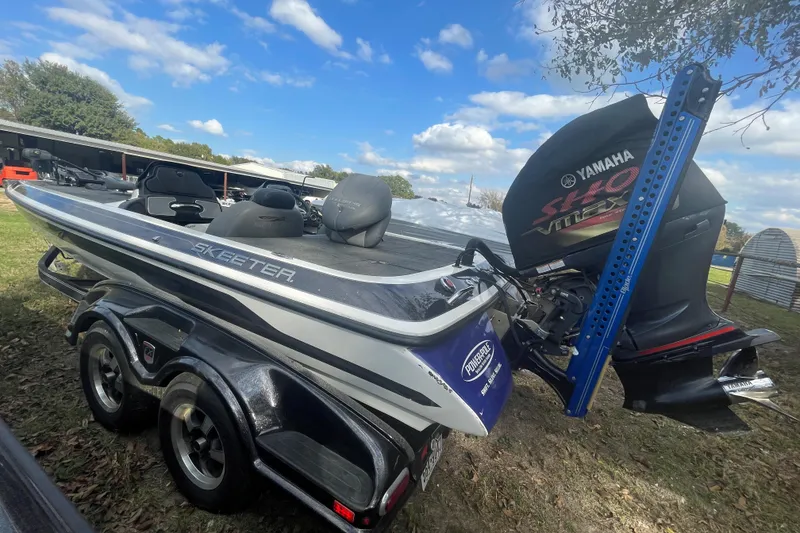 Slide: The Image of 2013 Skeeter FX21 boat with Yamaha engine on trailer, parked outdoors under blue sky. - 2