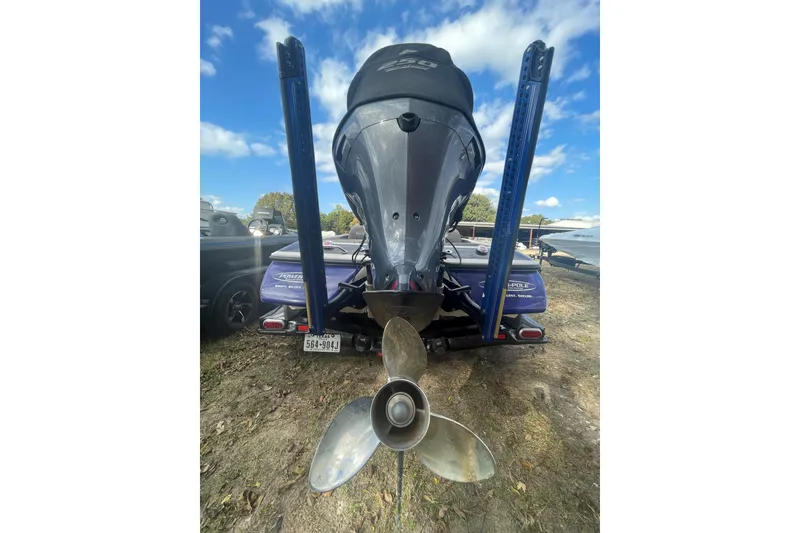 Slide: The Image of 2013 Skeeter FX21 boat rear view with motor and propeller, parked outdoors under blue sky. - 8