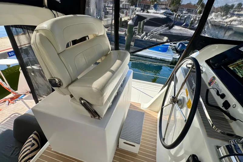 Slide: The Image of Captain's seat and helm of a 2020 Lagoon 42 catamaran, docked at a marina. - 5