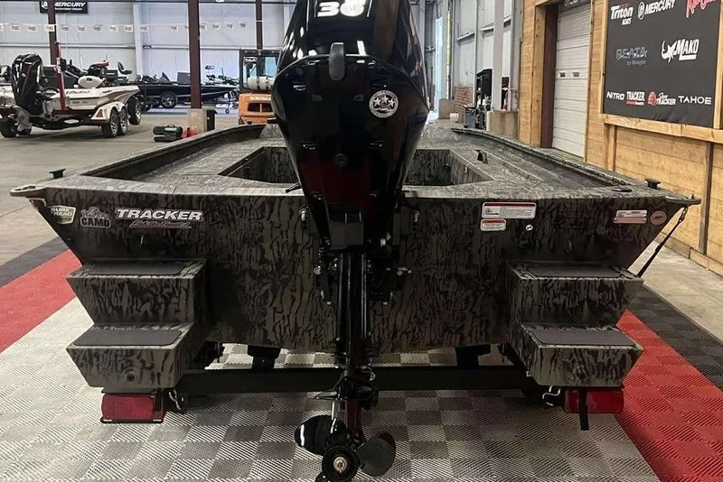 Slide: The Image of 2026 Tracker Grizzly 1654 Sportsman boat in showroom, rear view with motor. - 2