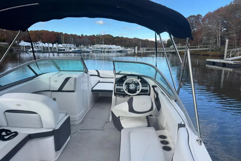 Slide: The Image of 2017 Regal 23 OBX boat interior with steering wheel, docked in a serene marina. - 8