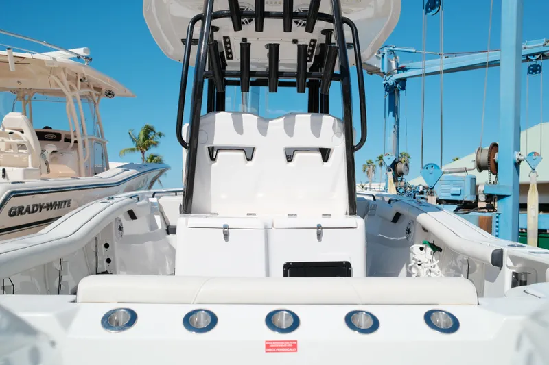 Slide: The Image of 2021 Tidewater 292 CC Adventure boat interior with seating and console, docked under clear blue sky. - 23