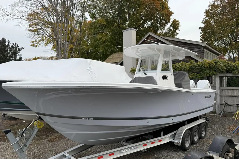 The Image of 2026 Regulator 28 boat on trailer, parked outdoors with trees in the background. - 0