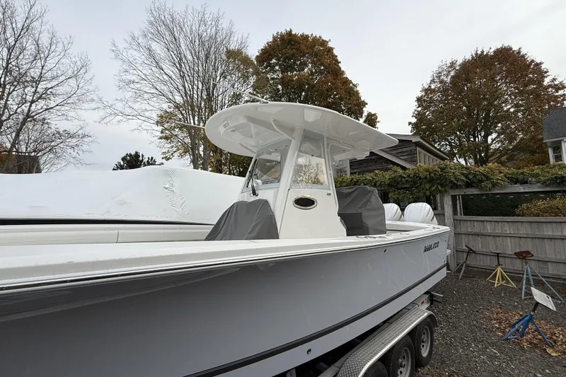 Slide: The Image of 2026 Regulator 28 boat on trailer, parked outdoors with autumn trees in the background. - 2