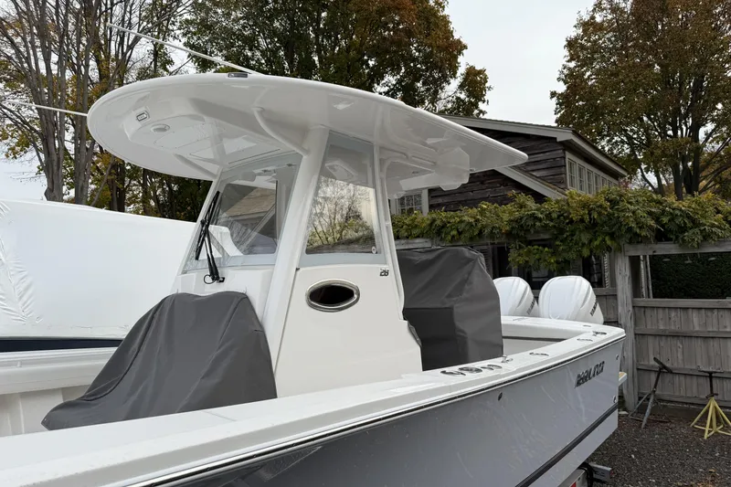 Slide: The Image of 2026 Regulator 28 boat with covered seats, docked near a wooden fence and trees. - 4