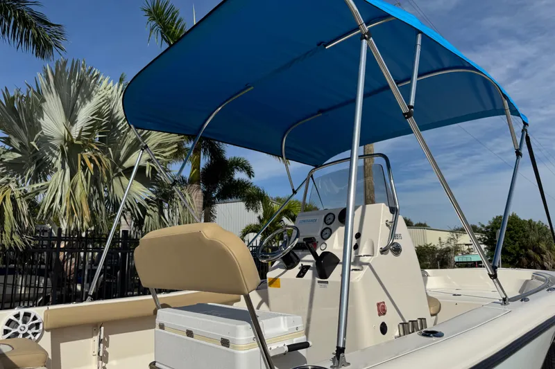 Slide: The Image of 2017 Key West 189 FS boat with blue canopy and palm trees in the background. - 87