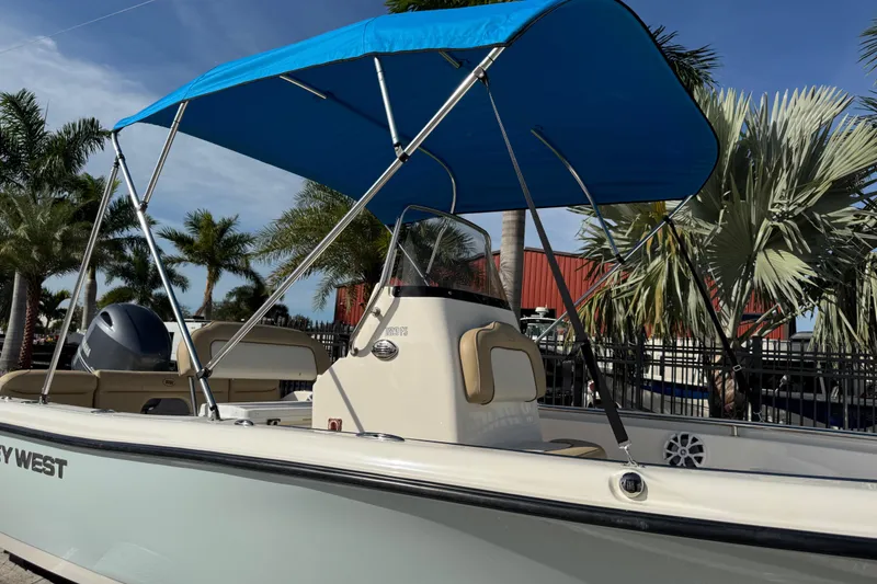 Slide: The Image of 2017 Key West 189 FS boat with blue canopy, parked near palm trees. - 89