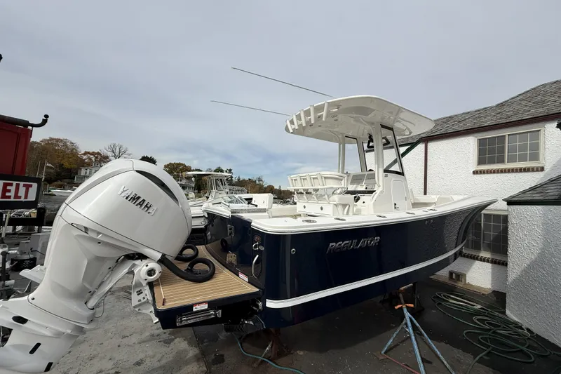 Slide: The Image of 2026 Regulator 25 boat with Yamaha engine, docked near a building. - 2