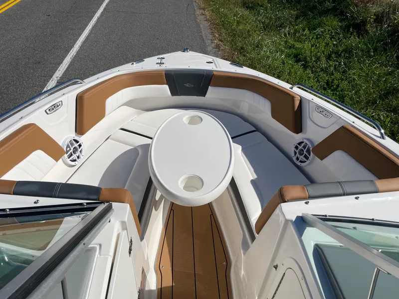 Slide: The Image of 2024 Chaparral 23 SSi OB boat interior with white and tan seating and round table. - 15