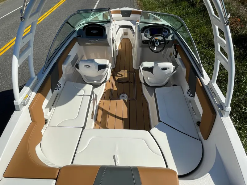 Slide: The Image of 2024 Chaparral 23 SSi OB boat interior with tan and white seating, and a sleek dashboard. - 36