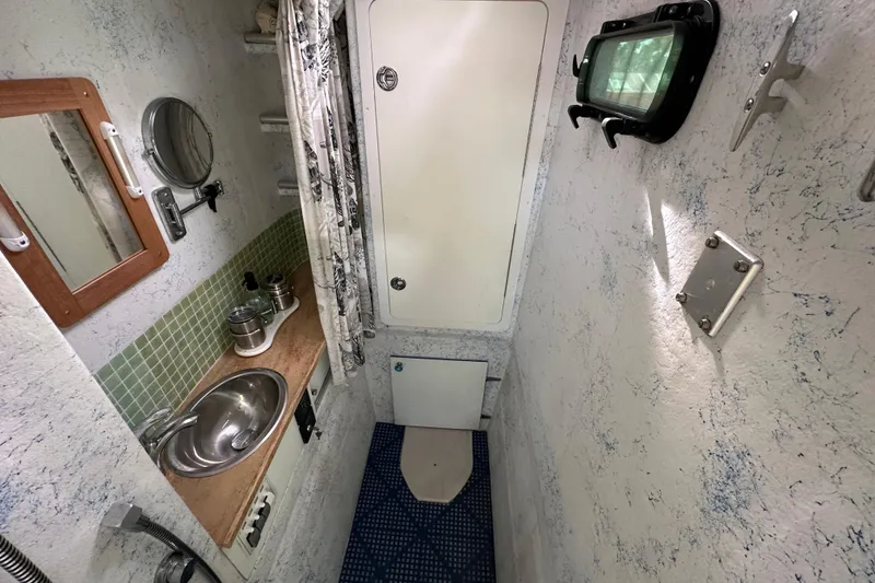 Slide: The Image of Compact bathroom in a 1999 Catamaran Coaches 31, featuring a sink, mirror, and shower area. - 15