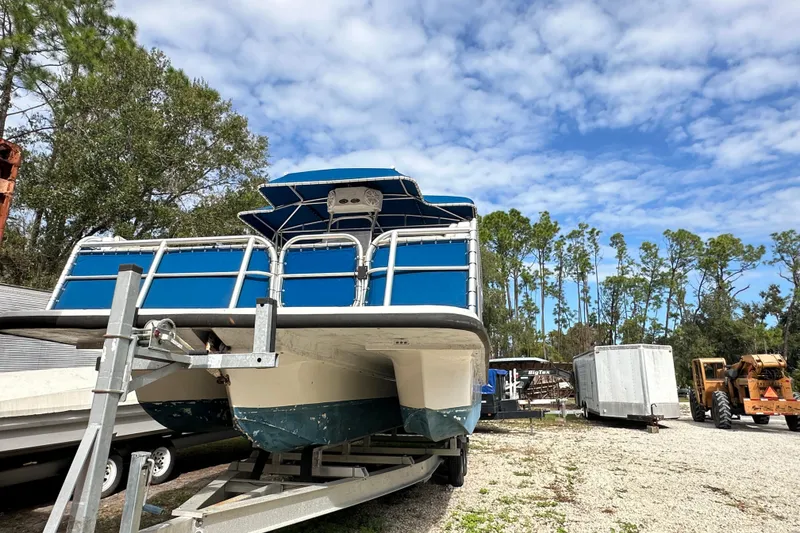 Slide: The Image of 1999 Catamaran Coaches 31 boat on trailer, surrounded by trees and equipment. - 16
