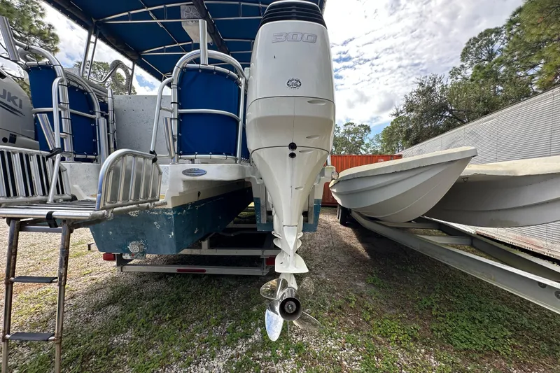 Slide: The Image of 1999 Catamaran Coaches 31 with outboard motor, parked outdoors on gravel. - 18