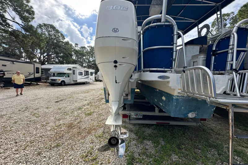 Slide: The Image of 1999 Catamaran Coaches 31 with outboard motor in a gravel lot, RVs in background. - 19