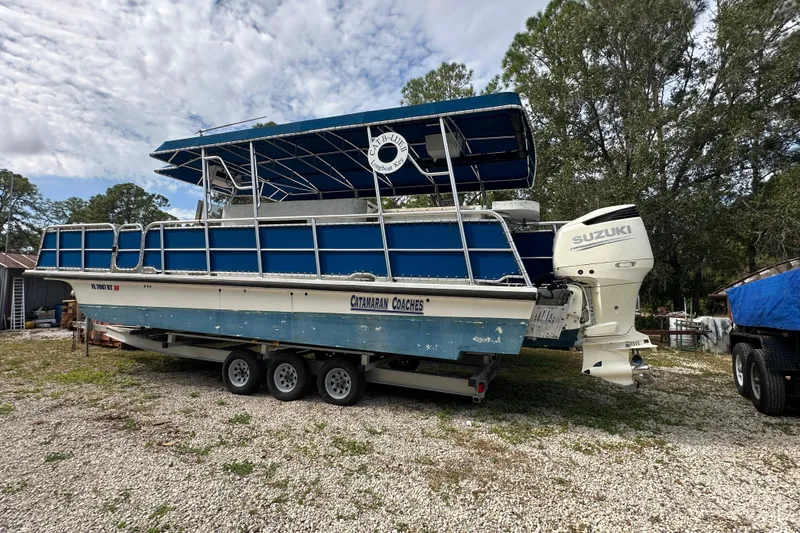 Slide: The Image of 1999 Catamaran Coaches 31 boat with Suzuki engine on a trailer, parked outdoors. - 3