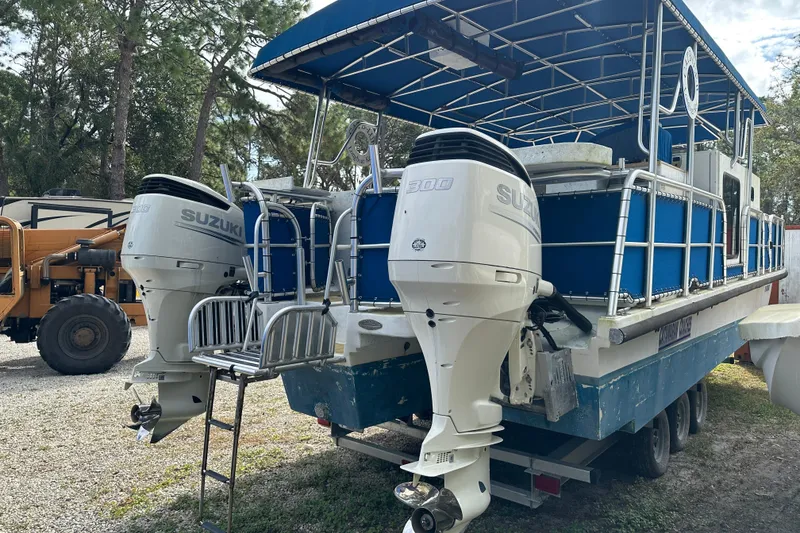 Slide: The Image of 1999 Catamaran Coaches 31 with dual Suzuki outboard motors, parked outdoors. - 4