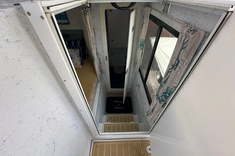 Slide: The Image of Interior view of a 1999 Catamaran Coaches 31, featuring a narrow hallway and window. - 9