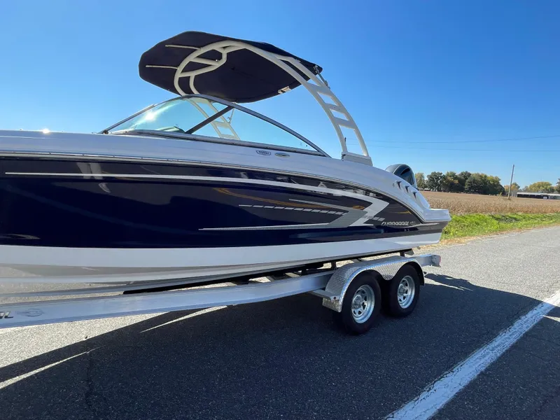 Slide: The Image of 2024 Chaparral 23 SSi OB boat on a trailer with a blue hull and bimini top. - 1