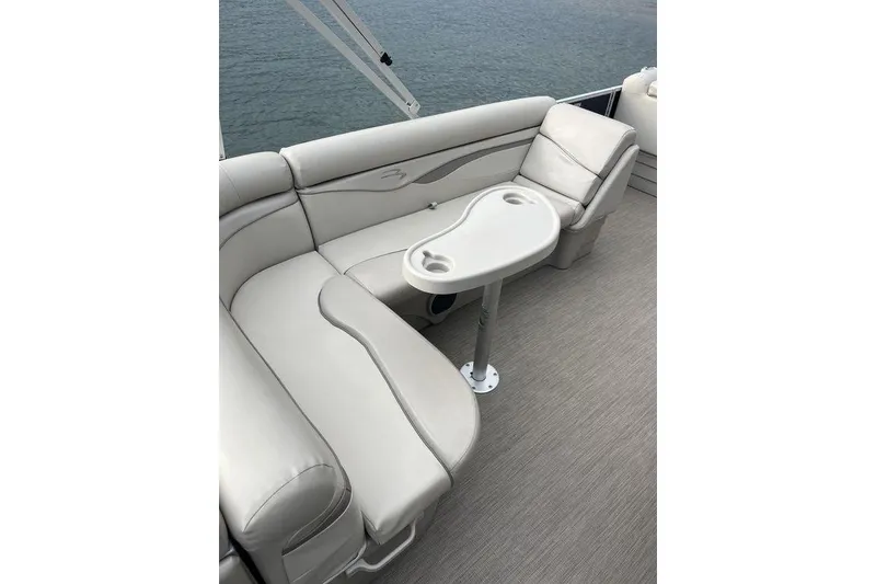 Slide: The Image of 2018 Bennington 23SLX pontoon boat interior with beige seating and table on water. - 11