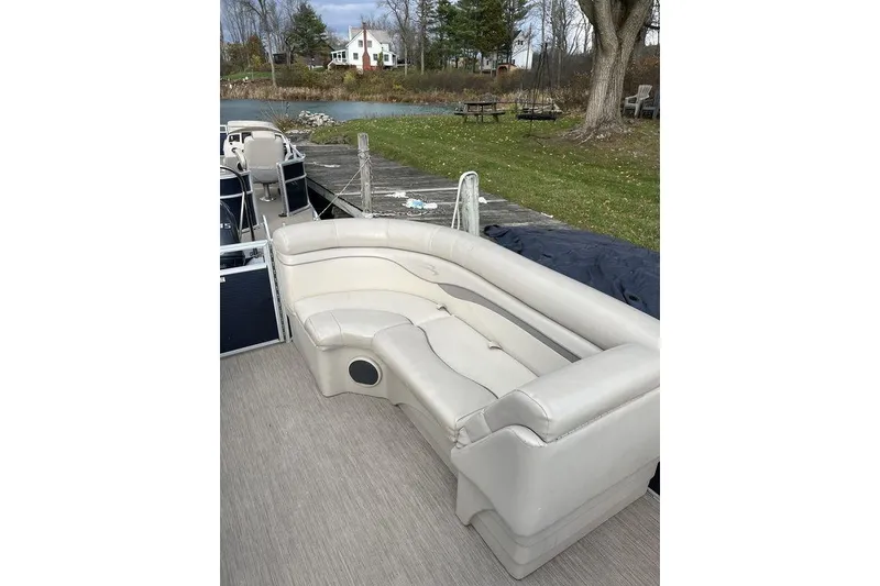 Slide: The Image of 2018 Bennington 23SLX pontoon boat with beige seating, docked by a serene lakeside. - 13
