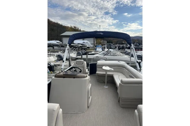 Slide: The Image of 2018 Bennington 23SLX pontoon boat with spacious seating and canopy, docked at marina. - 9