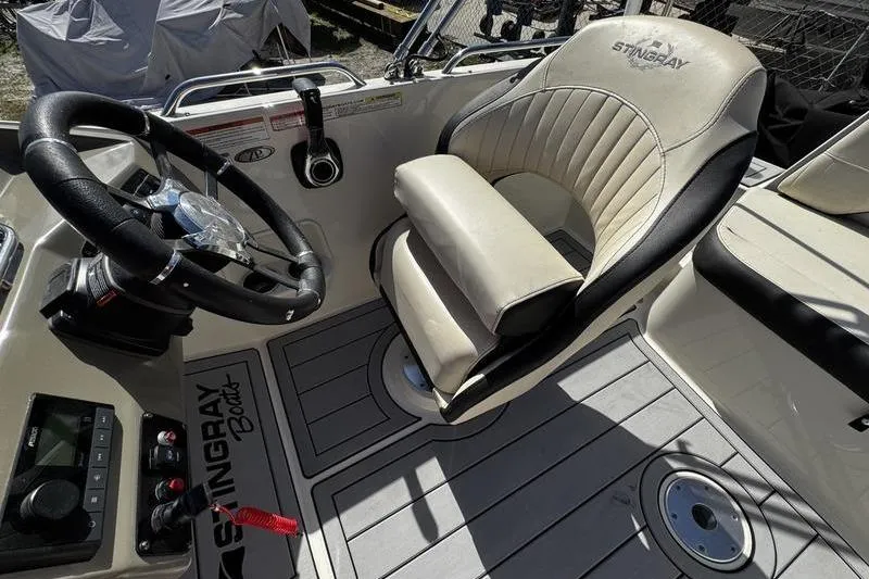 Slide: The Image of 2022 Stingray 212SC boat interior with steering wheel and cushioned captain's chair. - 19