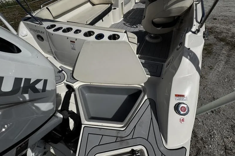 Slide: The Image of 2022 Stingray 212SC boat interior with seating, cup holders, and Suzuki engine. - 24