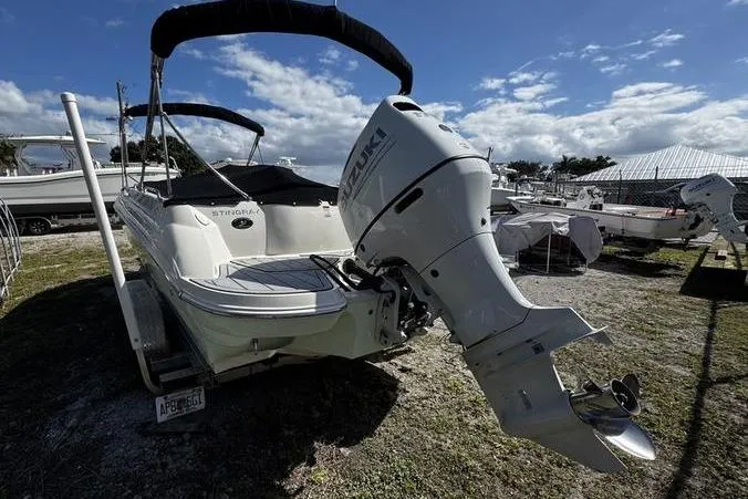 Slide: The Image of 2022 Stingray 212SC boat with Suzuki outboard motor, parked outdoors under a blue sky. - 29