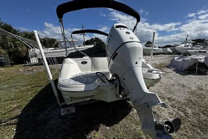 Slide: The Image of 2022 Stingray 212SC boat with outboard motor, parked on grassy area under blue sky. - 30