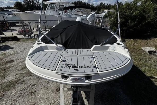 Slide: The Image of 2022 Stingray 212SC boat with covered deck, docked outdoors. - 4