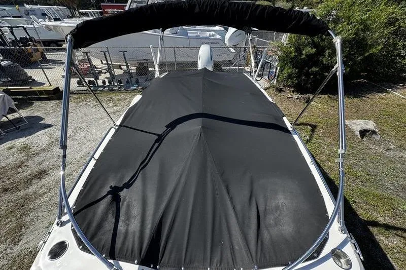 Slide: The Image of 2022 Stingray 212SC boat with black cover and canopy, parked outdoors. - 7