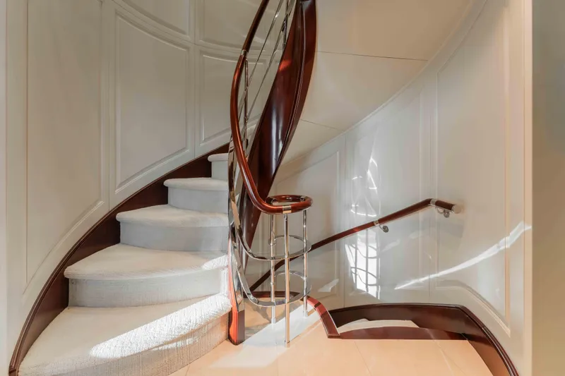 Slide: The Image of Elegant spiral staircase on 2004 Trinity Yachts motor yacht, featuring polished wood and plush carpeting. - 13
