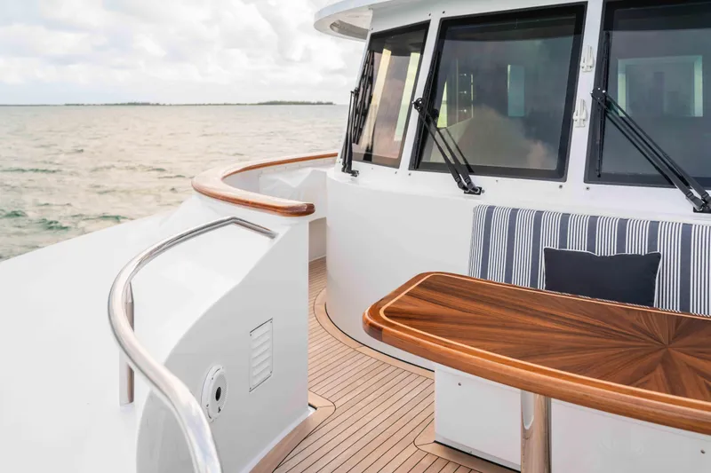 Slide: The Image of Luxurious 2004 Trinity Yachts motor yacht deck with elegant wood table and striped seating. - 32
