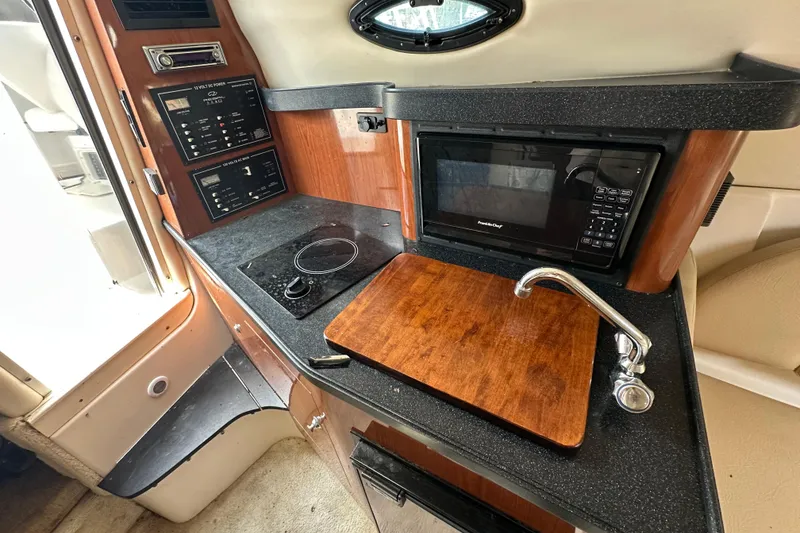 Slide: The Image of 2006 Regal Commodore 2665 boat interior kitchen with microwave, sink, and control panel. - 15
