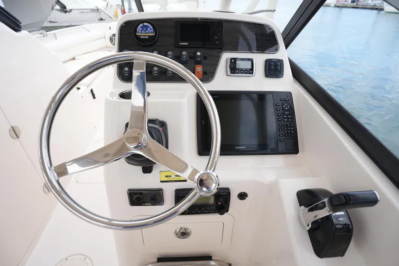 Slide: The Image of 2016 Grady-White Freedom 225 boat dashboard with steering wheel and navigation controls. - 23