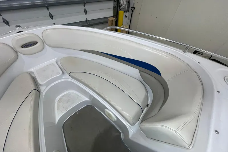 Slide: The Image of Interior seating of a 1999 Four Winns 220 Horizon boat, featuring white and blue upholstery. - 19