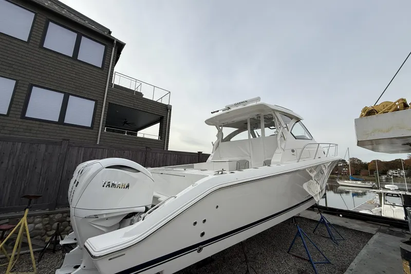 Slide: The Image of 2026 Pursuit OS 355 Offshore boat with Yamaha engine, docked near a modern building. - 2