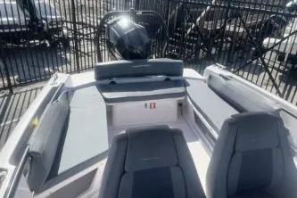 Slide: The Image of 2022 Axopar 22 TT boat interior with seating and motor, docked near a fence. - 10