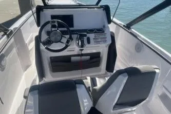 Slide: The Image of 2022 Axopar 22 TT boat cockpit with modern steering and controls, docked by the water. - 16