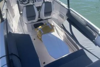 Slide: The Image of 2022 Axopar 22 TT boat interior with seating and steering console on water. - 17