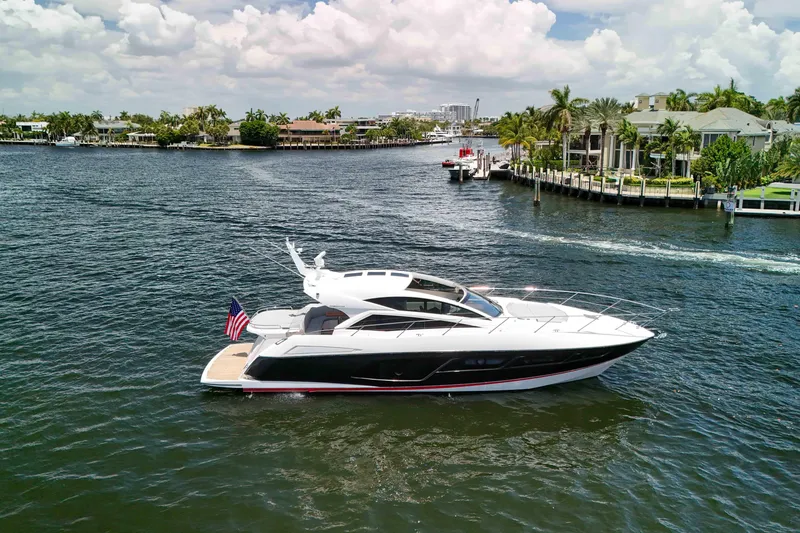 Slide: The Image of 2017 Sunseeker Predator 57 yacht cruising on a scenic waterway with luxury homes. - 1