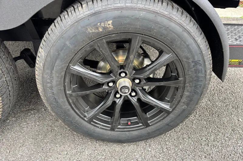 Slide: The Image of Black alloy wheel of 2026 Triton 19 TrX Patriot on asphalt surface. - 11