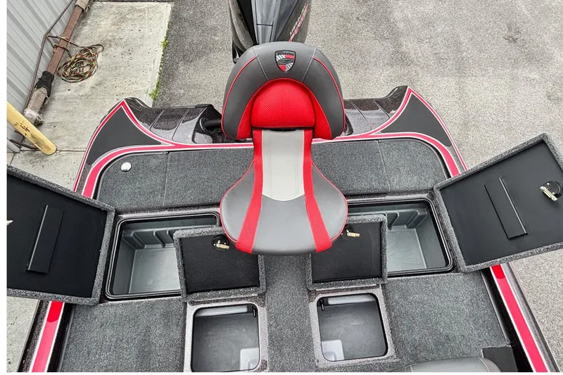 Slide: The Image of 2026 Triton 19 TrX Patriot boat interior with red and gray seat, open storage compartments. - 12