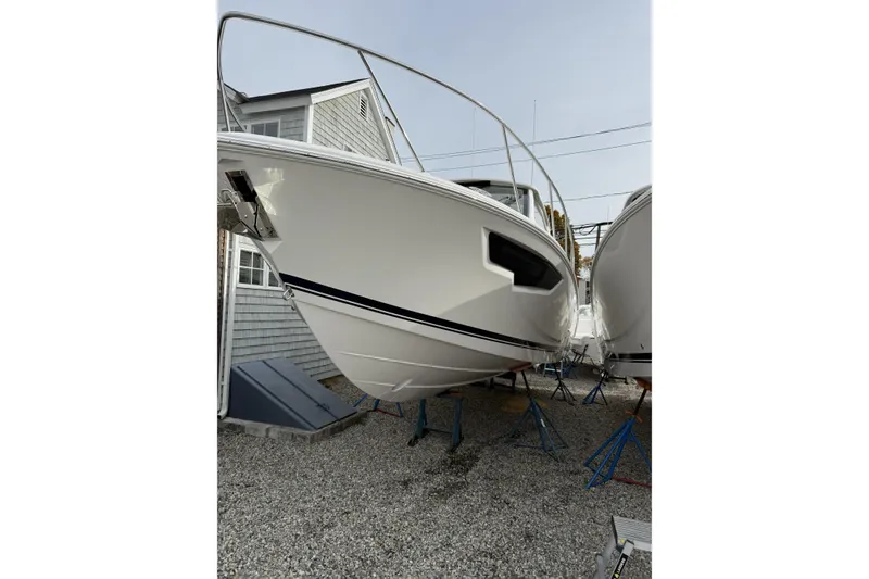 The Image of 2026 Pursuit OS 325 Offshore boat on stands, front view, near a house. - 0